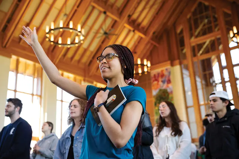 A student lifting her hands in worship amongst fellow students in the new chapel