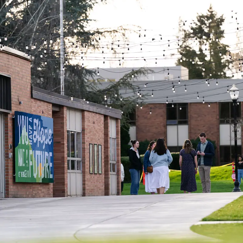 Students standing under string lights in Newberg's scenic campus