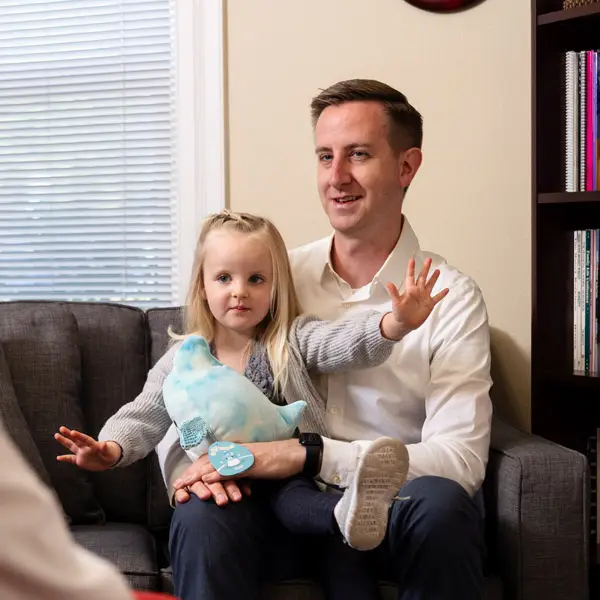 A father sits with his daughter in a psychiatric session