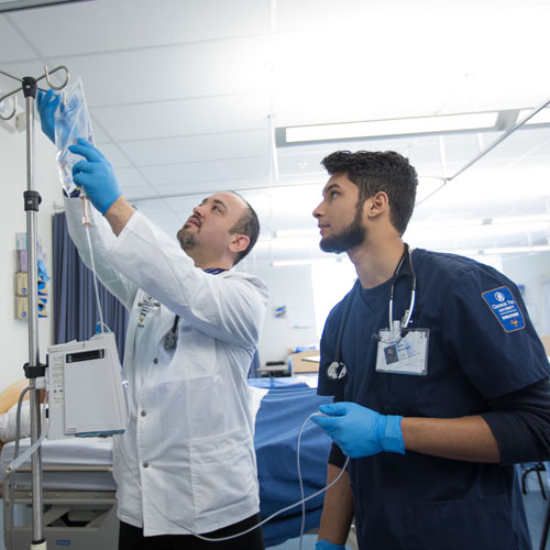 Nurse practitioner shows a nursing student how to run an IV