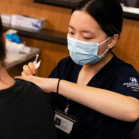 Nursing student administering vaccine to a patient