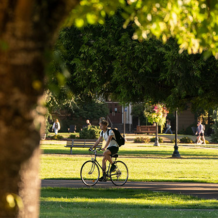 A student on a bike to class on campus