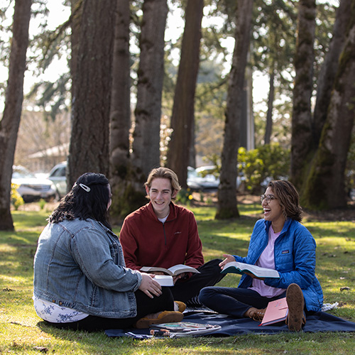 Three students in small group Bible study outdoor on campus