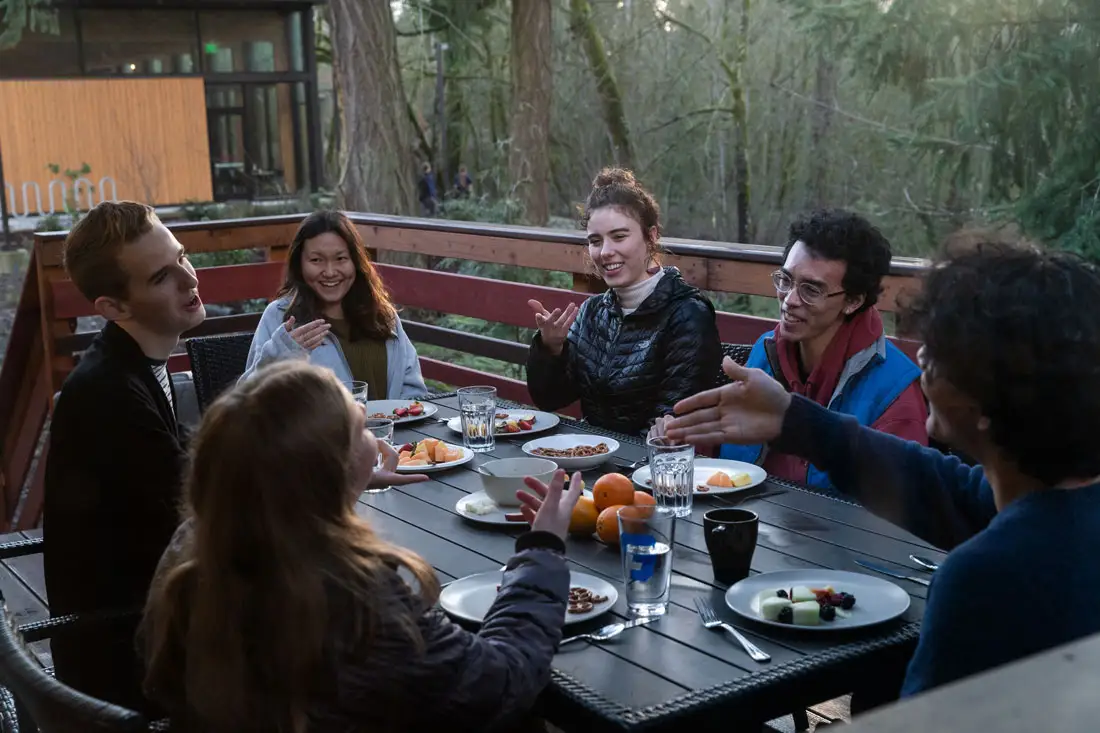 Student eating around a table on a porch in the pacific northwest