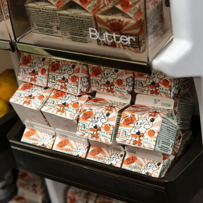 A refrigerator shelf full of orange juice cartons