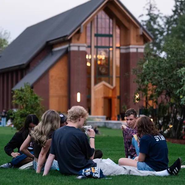 students sit in front of the chapel in a small group