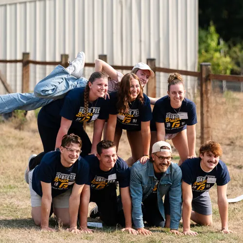 7 students form an unfinished human pyramid to pose for a photo