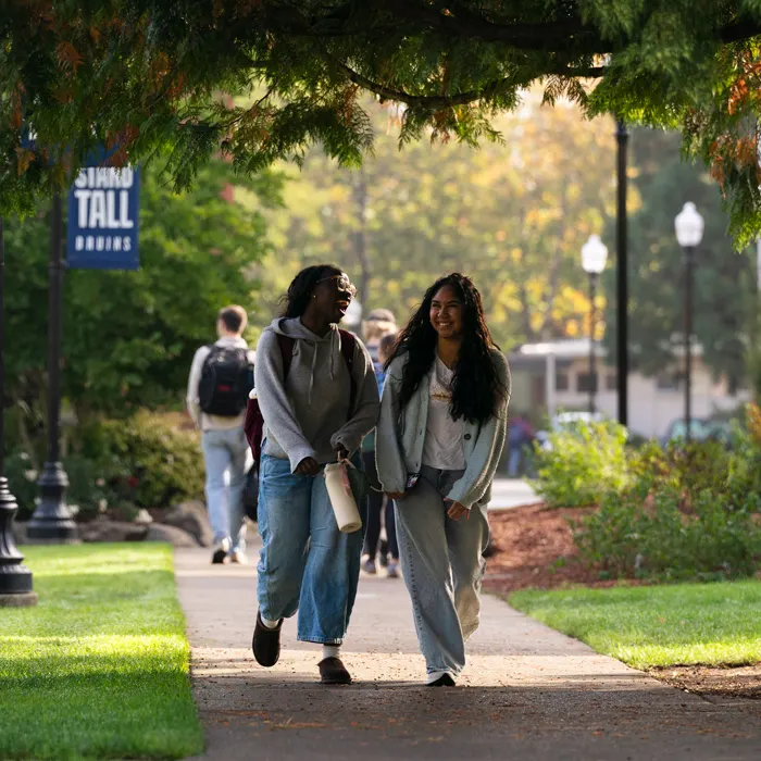 two roommates walk and laugh together on the quad