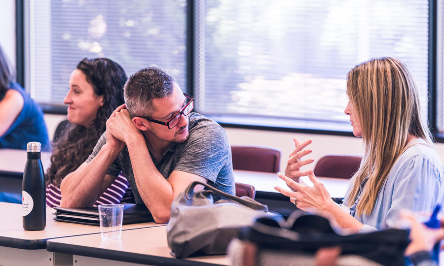 2 seminary students sit at a table in a classroom