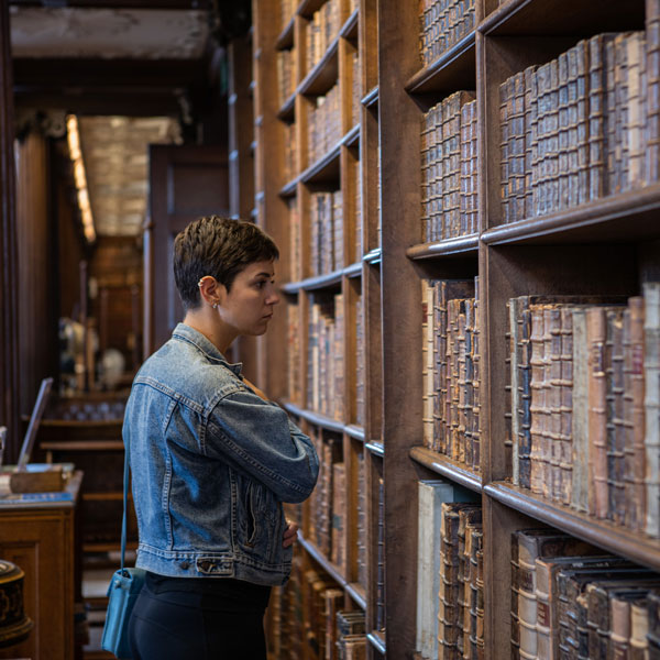 Student stands in library looking through books