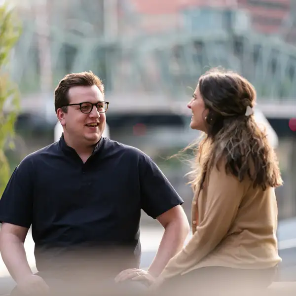 Two people sitting by the waterfront while one joyfully shares and one listens