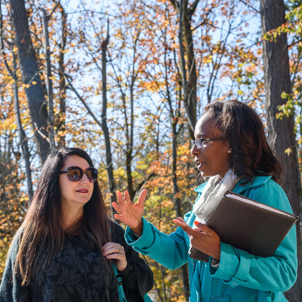 two students talk outdoors in the sun