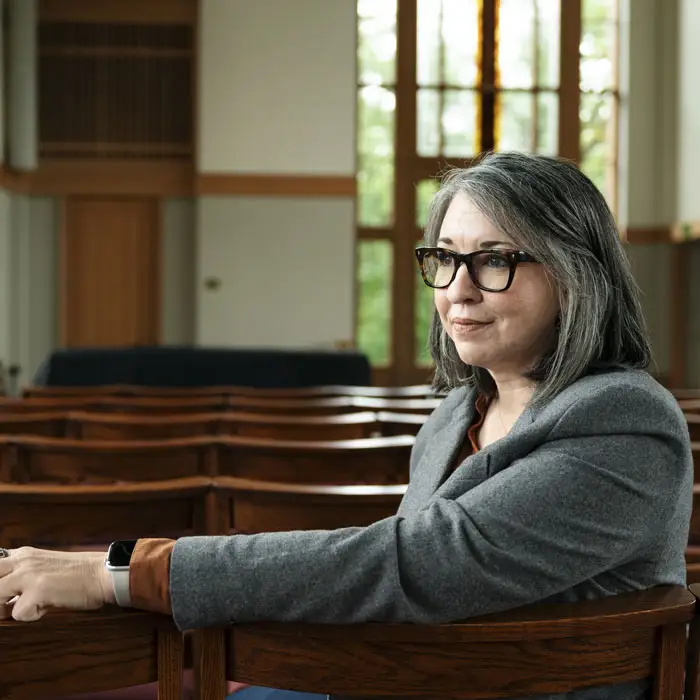 A woman sitting a pew looking out in contemplation
