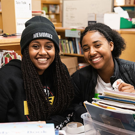 two students helping to organize files in the local library